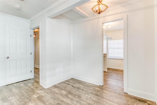 spare room featuring a chandelier, ornamental molding, and light hardwood / wood-style flooring