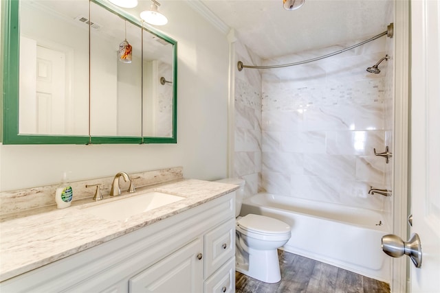 full bathroom featuring tiled shower / bath, toilet, wood-type flooring, vanity, and crown molding