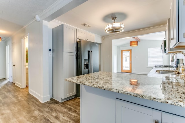 kitchen with white cabinets, light stone countertops, ornamental molding, sink, and high end fridge