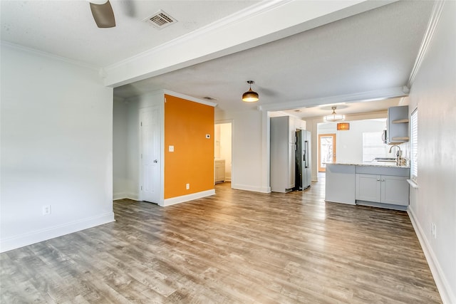 unfurnished living room featuring ornamental molding, light hardwood / wood-style flooring, and sink