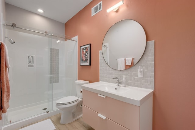 bathroom with a shower with shower door, tasteful backsplash, hardwood / wood-style floors, toilet, and vanity