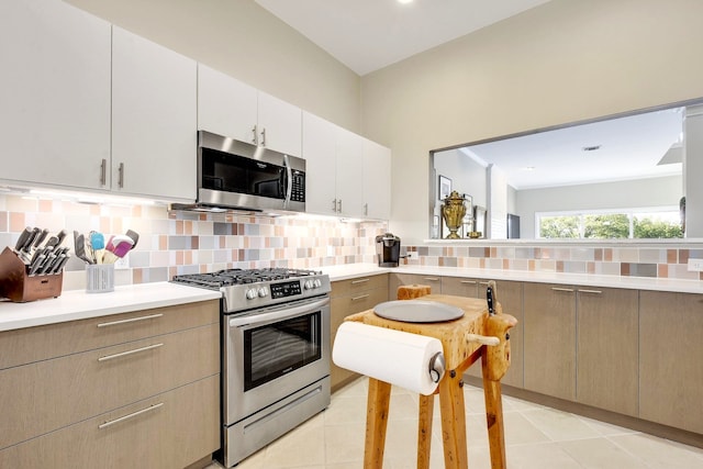 kitchen with appliances with stainless steel finishes, light tile patterned flooring, and backsplash