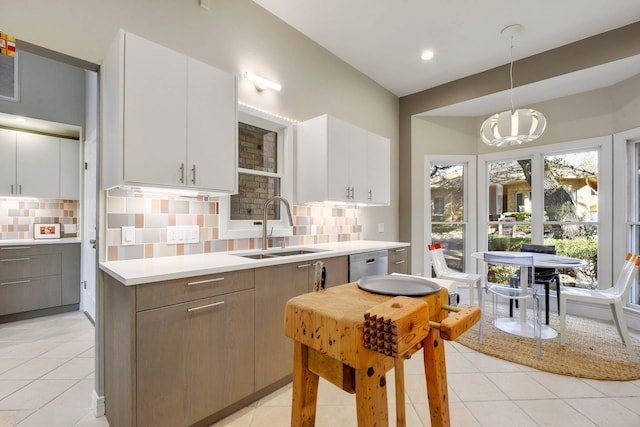 kitchen featuring dishwasher, decorative light fixtures, backsplash, white cabinets, and sink