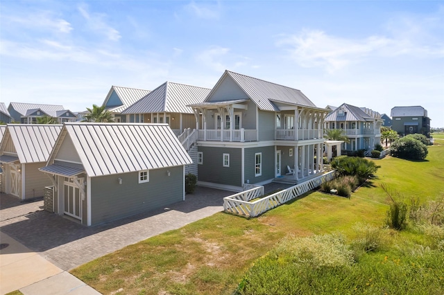 rear view of property featuring a lawn, covered porch, and a balcony