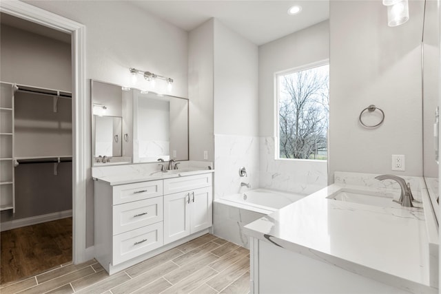 bathroom featuring tiled tub and vanity