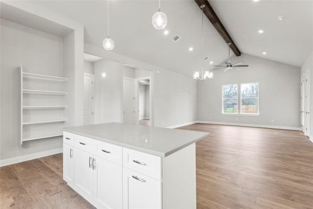 kitchen featuring pendant lighting, ceiling fan with notable chandelier, a center island, and white cabinets