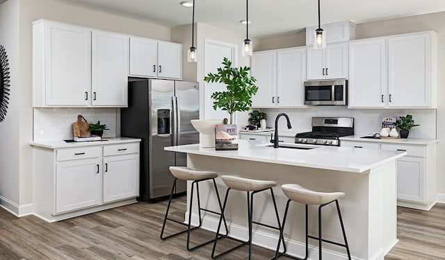 kitchen with stainless steel appliances, an island with sink, and white cabinetry