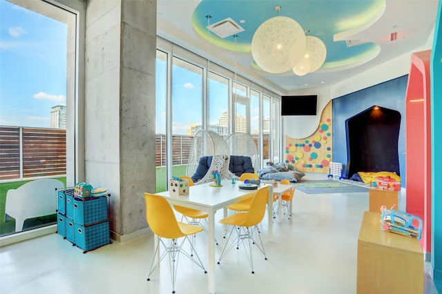 interior space with a raised ceiling, concrete floors, and a wealth of natural light