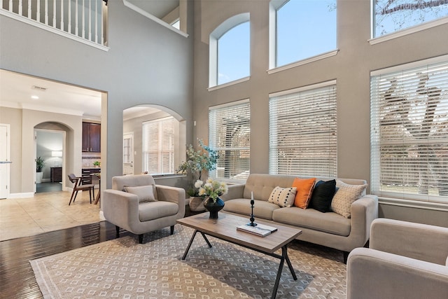 living room featuring light tile patterned floors, a wealth of natural light, ornamental molding, and a high ceiling