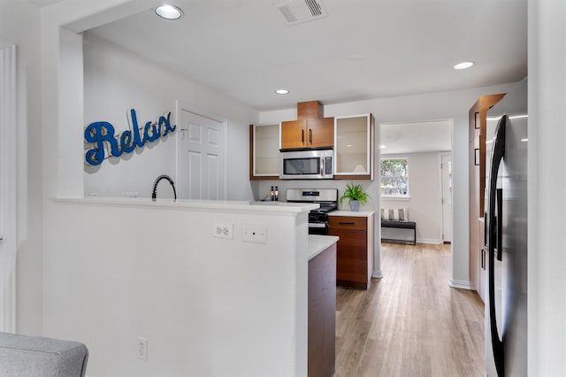 kitchen featuring stainless steel appliances, light hardwood / wood-style flooring, and kitchen peninsula