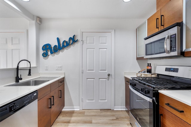 kitchen featuring stainless steel appliances, light wood-type flooring, and sink