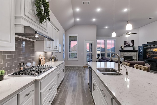 kitchen with vaulted ceiling, hanging light fixtures, white cabinetry, appliances with stainless steel finishes, and sink