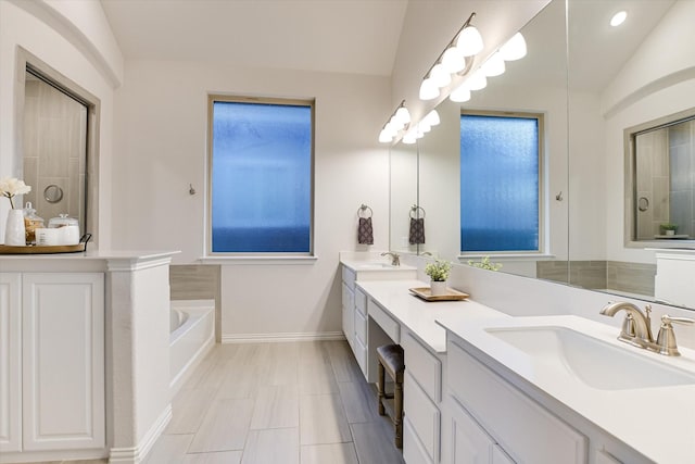 bathroom with lofted ceiling, vanity, and a washtub