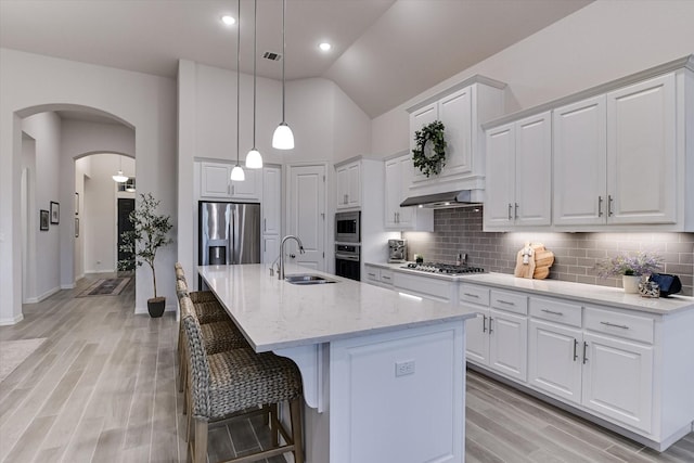 kitchen featuring stainless steel appliances, white cabinetry, sink, and an island with sink