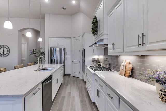 kitchen with stainless steel appliances, sink, white cabinetry, decorative backsplash, and pendant lighting