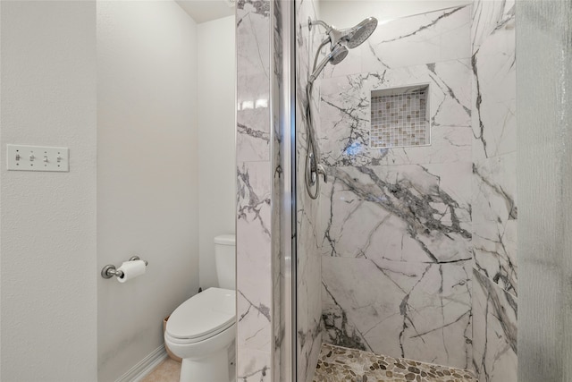 bathroom featuring a tile shower and toilet