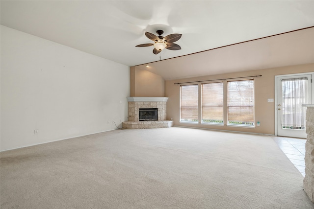 unfurnished living room with ceiling fan, light colored carpet, vaulted ceiling, and a fireplace