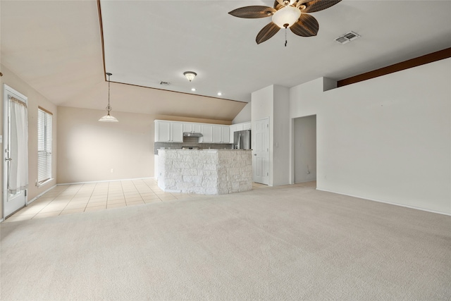 unfurnished living room with ceiling fan, vaulted ceiling, and light carpet