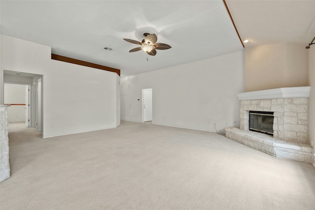 unfurnished living room featuring light colored carpet, ceiling fan, and a stone fireplace