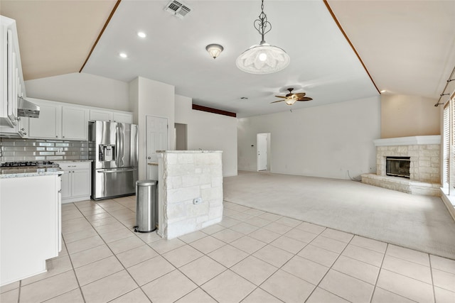 kitchen featuring white cabinets, a fireplace, light carpet, ceiling fan, and stainless steel fridge