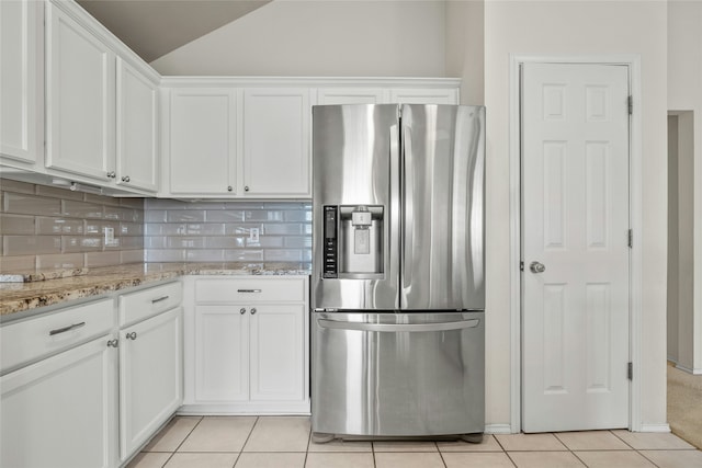 kitchen with white cabinets, stainless steel fridge, light stone countertops, and light tile patterned floors