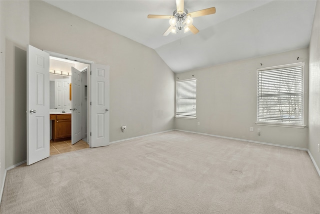 unfurnished bedroom with ceiling fan, connected bathroom, vaulted ceiling, and light carpet