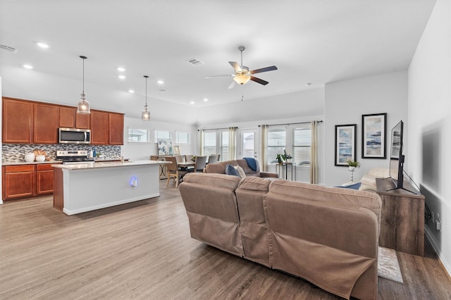 living room featuring ceiling fan, a healthy amount of sunlight, and light hardwood / wood-style flooring