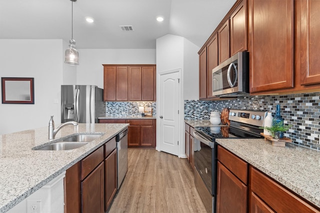 kitchen featuring appliances with stainless steel finishes, light stone countertops, sink, light hardwood / wood-style flooring, and decorative light fixtures