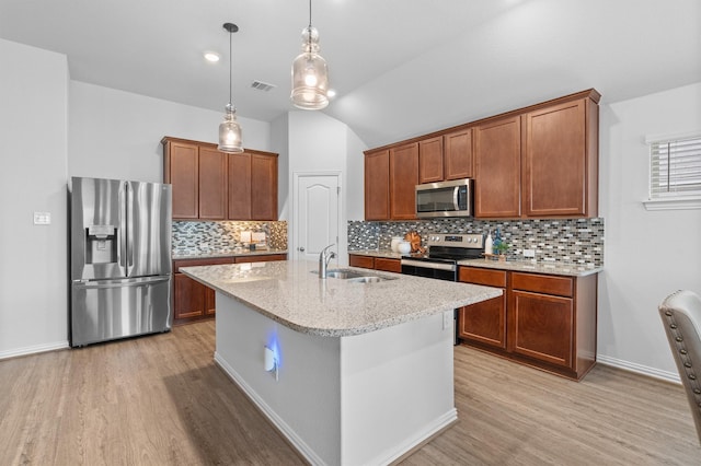 kitchen with stainless steel appliances, sink, a kitchen island with sink, and light hardwood / wood-style flooring