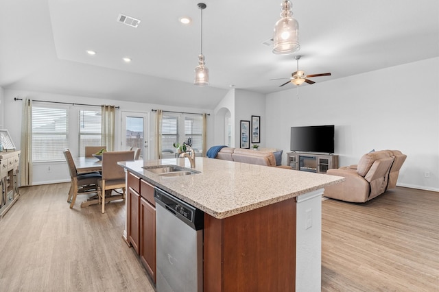 kitchen with sink, light wood-type flooring, stainless steel dishwasher, hanging light fixtures, and a center island with sink