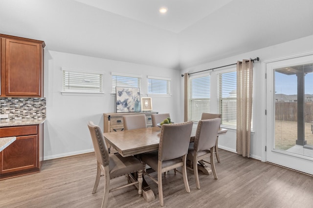 dining room featuring light wood-type flooring and vaulted ceiling