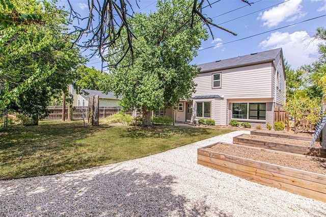 view of front facade with fence, a vegetable garden, and a front lawn