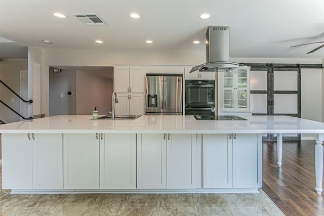 kitchen with island exhaust hood, a large island, visible vents, a sink, and black appliances