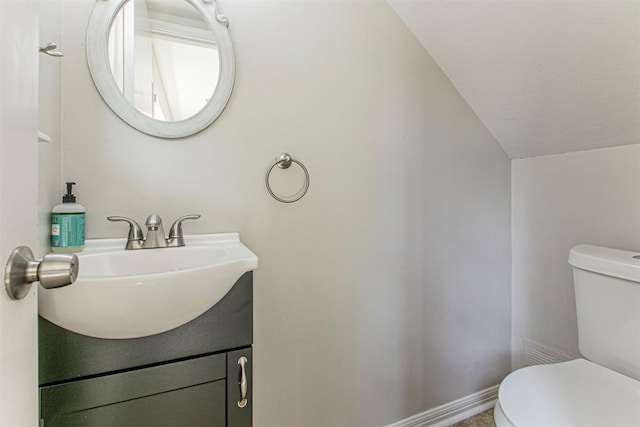 half bath featuring vaulted ceiling, vanity, toilet, and baseboards