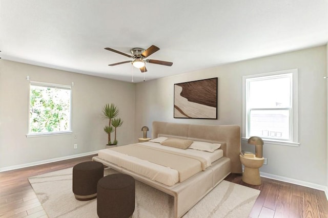 bedroom with wood-type flooring, a ceiling fan, and baseboards