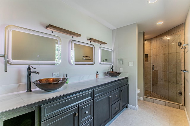 bathroom with double vanity, a stall shower, a sink, and tile patterned floors