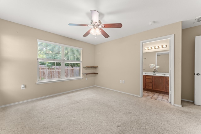 unfurnished bedroom featuring ceiling fan, light carpet, and ensuite bath