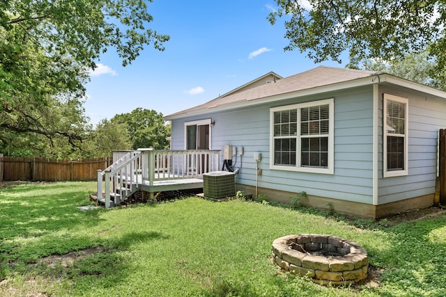 rear view of property featuring a yard, an outdoor fire pit, central AC, and a wooden deck