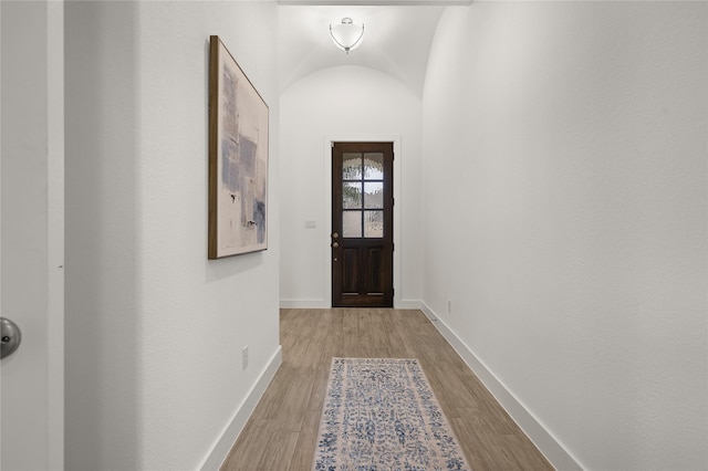 doorway with light hardwood / wood-style floors and vaulted ceiling