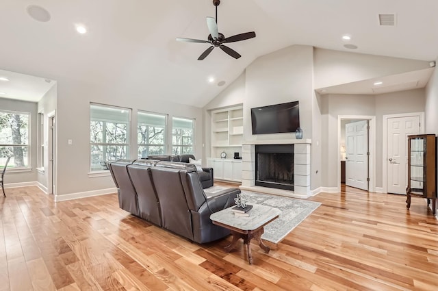 living room with ceiling fan, built in shelves, high vaulted ceiling, and light hardwood / wood-style floors