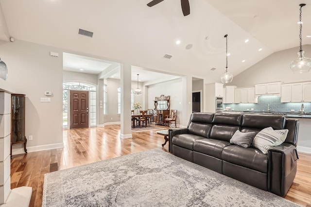 living room featuring ceiling fan, high vaulted ceiling, and light wood-type flooring