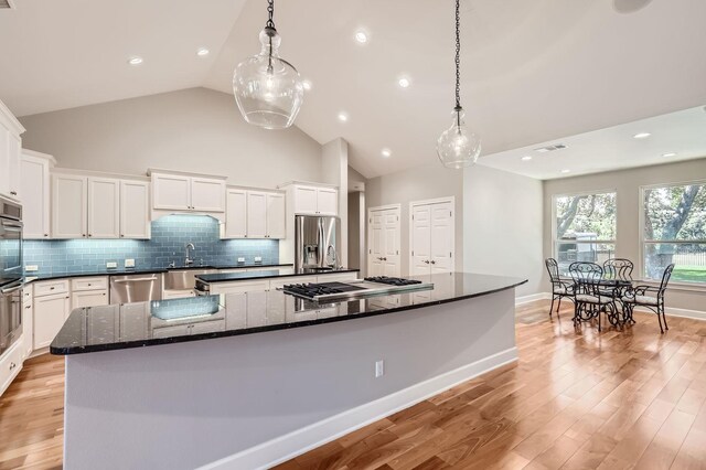 kitchen with a spacious island, white cabinetry, stainless steel appliances, hanging light fixtures, and backsplash