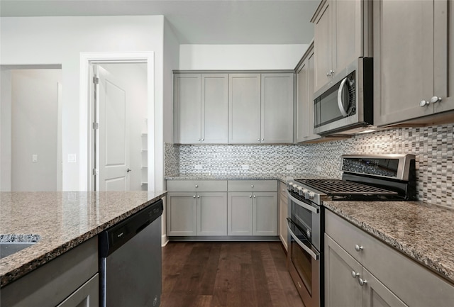 kitchen featuring stainless steel appliances, light stone counters, gray cabinets, tasteful backsplash, and dark hardwood / wood-style floors