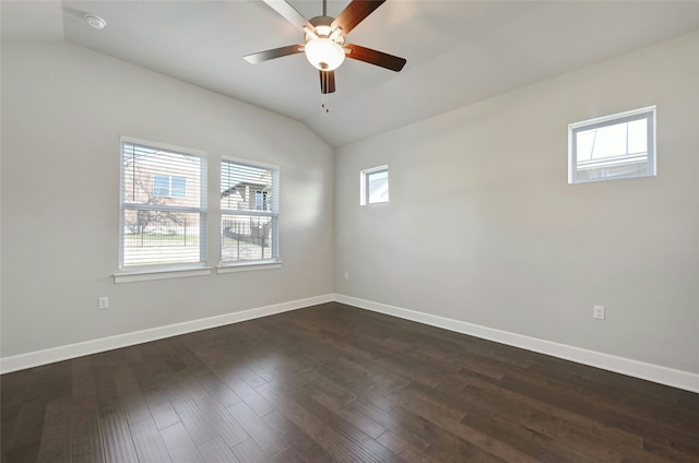 empty room with ceiling fan, vaulted ceiling, a wealth of natural light, and dark hardwood / wood-style floors