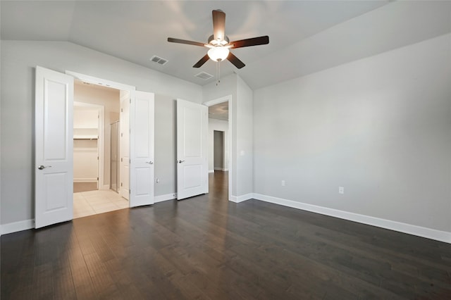 unfurnished bedroom featuring ceiling fan, vaulted ceiling, a spacious closet, and dark hardwood / wood-style floors