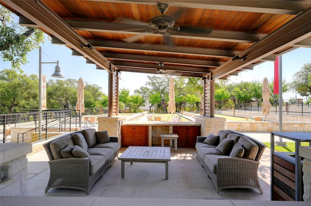 view of patio with ceiling fan, an outdoor hangout area, and a bar