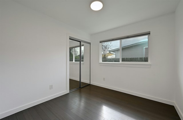 unfurnished bedroom with dark hardwood / wood-style flooring and a closet