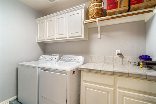 clothes washing area with washer and dryer and cabinets