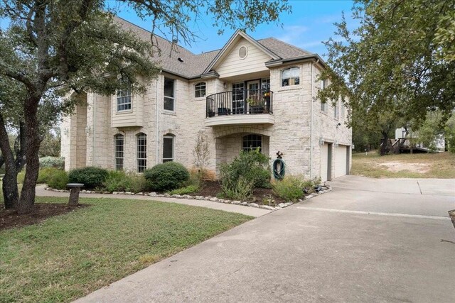 view of front facade with a balcony, a front lawn, and a garage