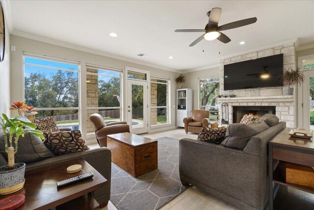 living room featuring hardwood / wood-style flooring, crown molding, ceiling fan, and a fireplace